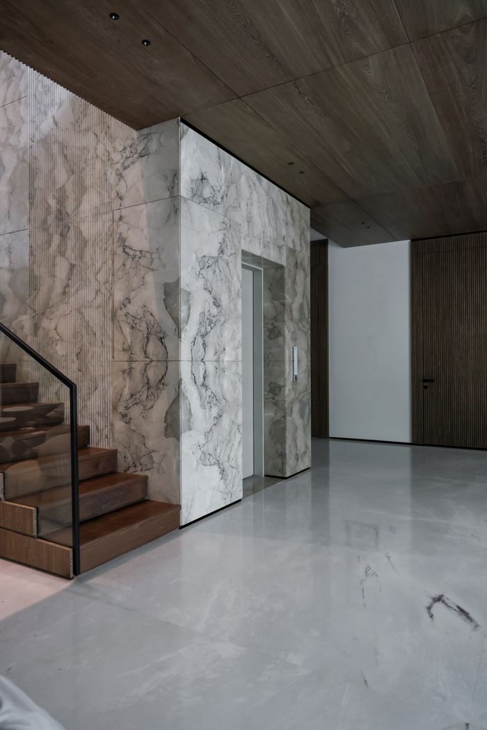 about-03 Sleek modern interior featuring marble walls and wooden staircase, exuding luxury.